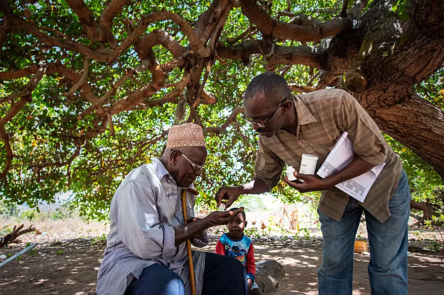 A community drug distributor gives medicine to a family at their home in Tanzania to help them prevent LF infection