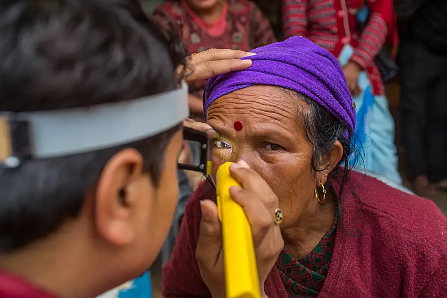 A trained grader from NNJS checks the eyes of a woman for clinical signs of trachoma during one of the last surveys before Nepal achieved validation of elimination of trachoma in 2018.