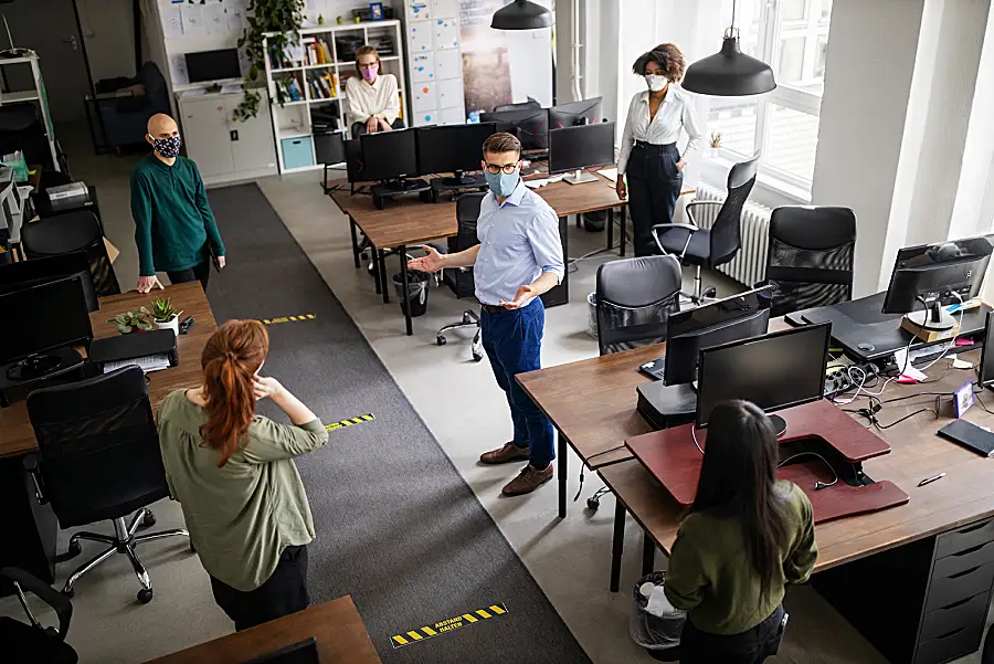 Workers use masks and social distancing while sharing office space during a pandemic.