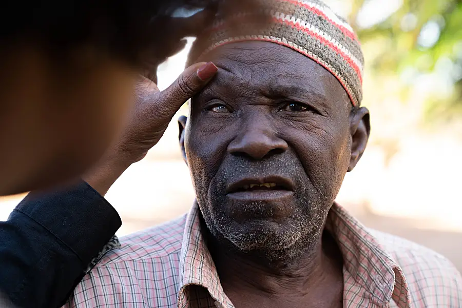 A senior man in Mozambique has his eyes checked for glaucoma