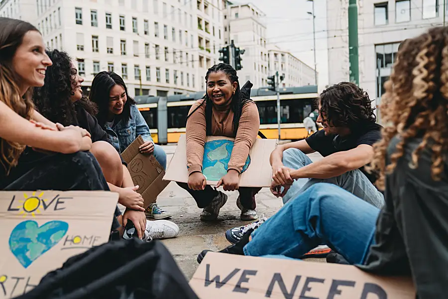 Photo of a group of young climate activists in a city sitting and talking with signs