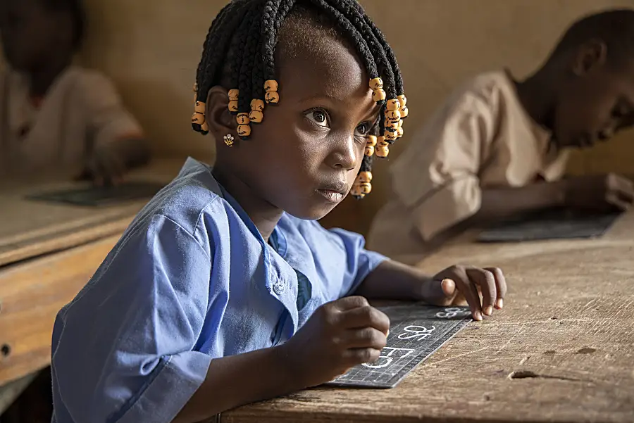 Girl with hand-held chalk board and piece of chalk in her hand