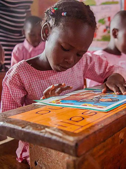 Ugandan schoolchildren practice reading in a classroom.