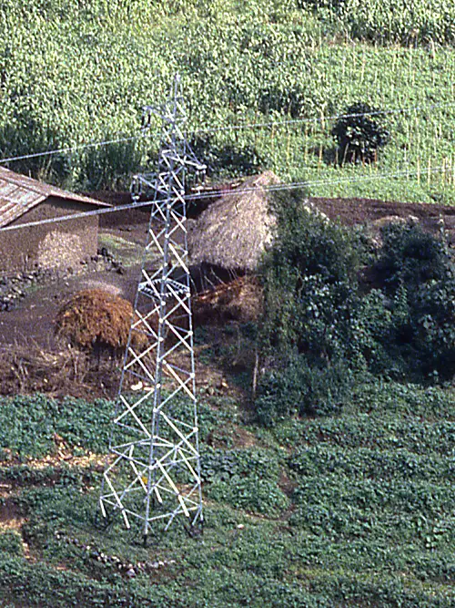 Power lines stretch over a traditional village in a wooded area of Rwanda.