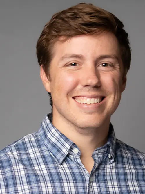 Headshot of Tyler Ovington smiling against a grey background