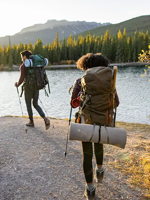 Photo of two backpackers hiking near a lake