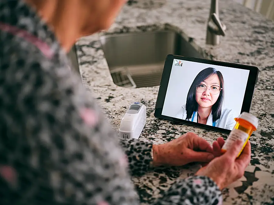 A senior woman meets with her doctor via a teleconferencing app on her phone.