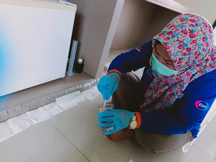 A technician in personal protective gear tests a sample.