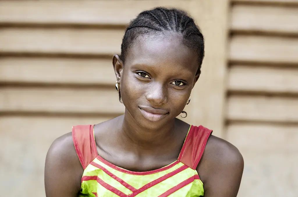 A teenage girl from Africa smiles at the camera.