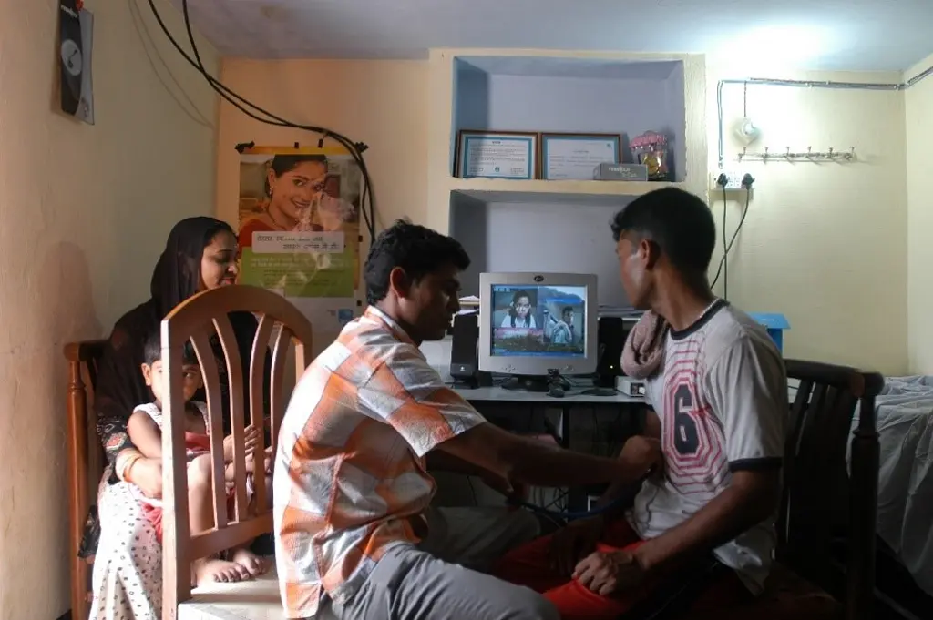 A family gathers around a computer monitor for a telehealth visit.