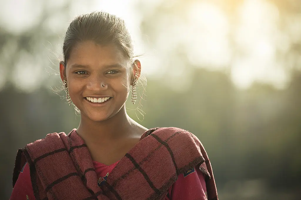 A teenage girl from rural India smiles at the camera.