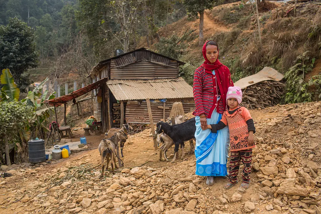 A female community health volunteer with her daughter in front of their home in Nepal.
