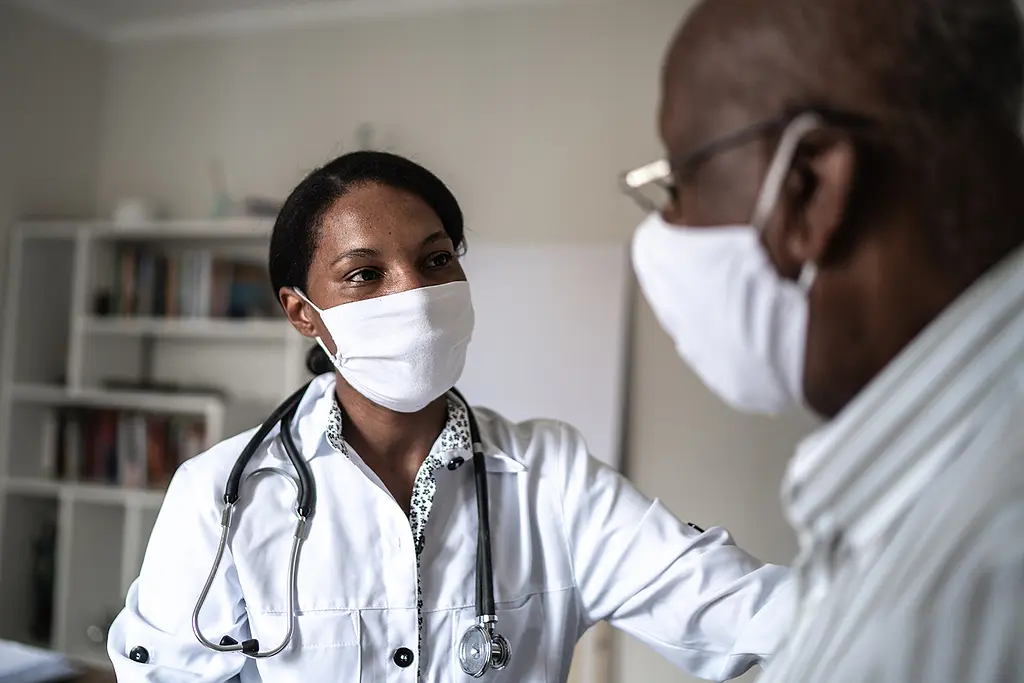 A Black female doctor works with a Black male patient.