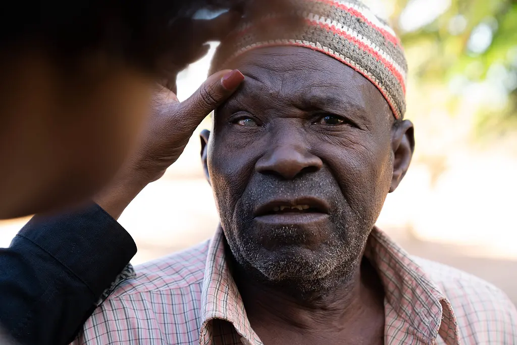 A senior man in Mozambique has his eyes checked for glaucoma