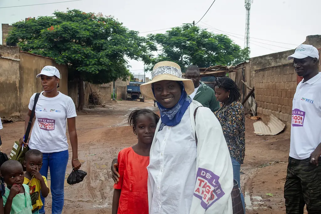 Seynabou Gaye smiling with children in a rural village