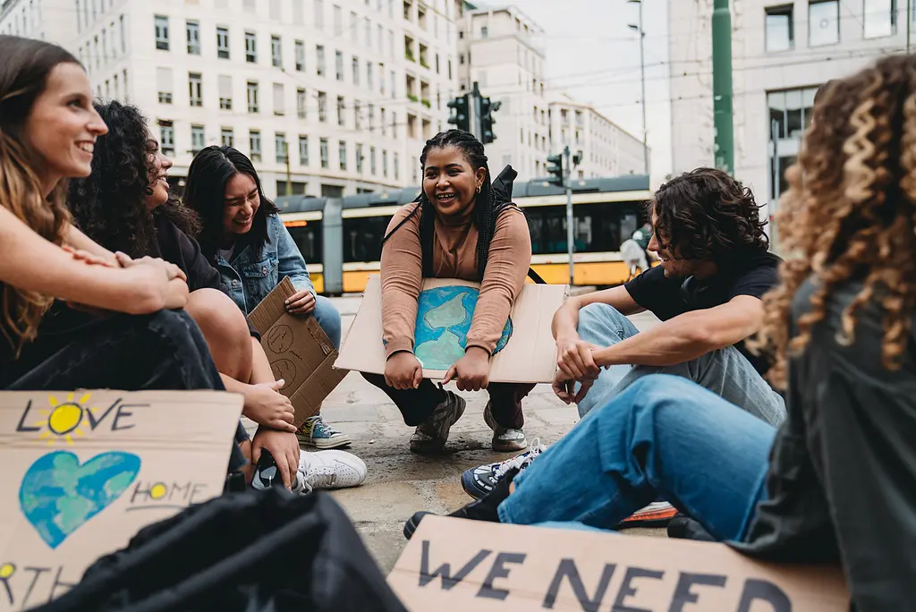 Photo of a group of young climate activists in a city sitting and talking with signs