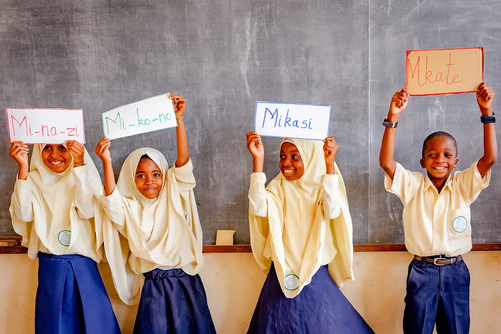 Tanzanian children hold up flash cards during a reading lesson.