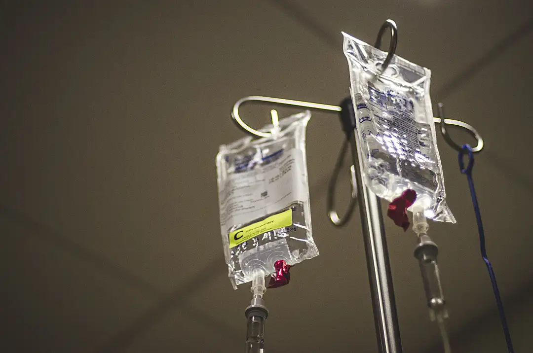 Two IV bags handing from metal pole. 