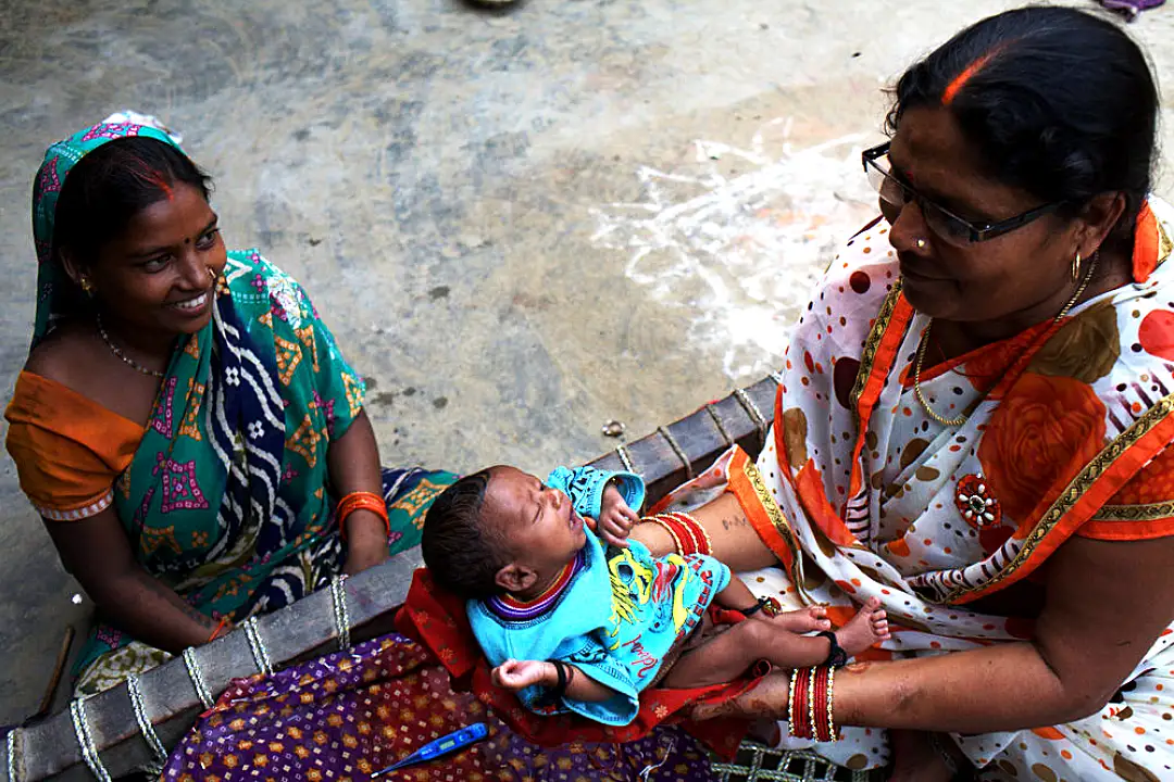 An accredited social health activist visits a mother and child at their home in an Indian village.