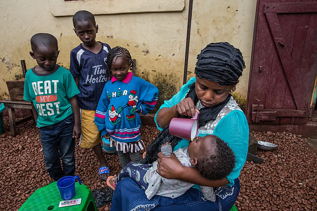 A mother in Guinea gives her baby a malaria preventive.