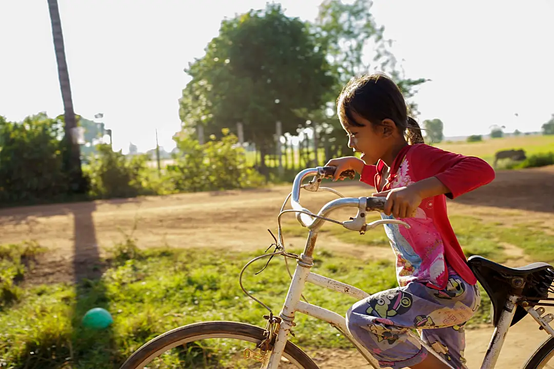 Photo of a young girl outside riding her bike