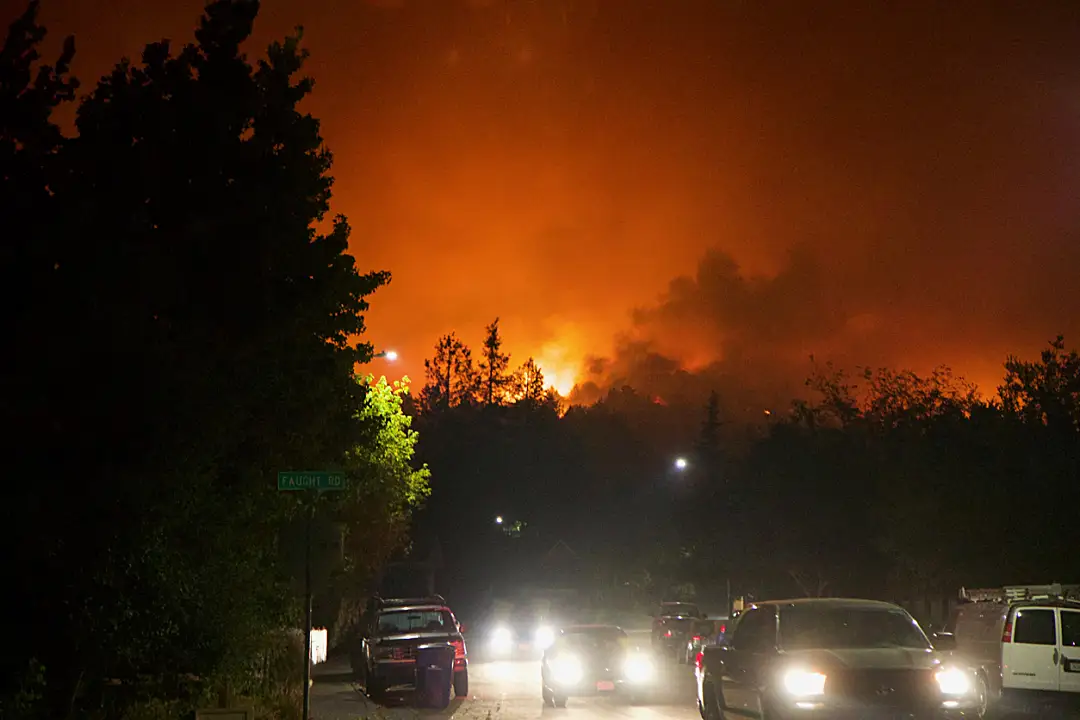 cars on a road with forest fires in the distance.