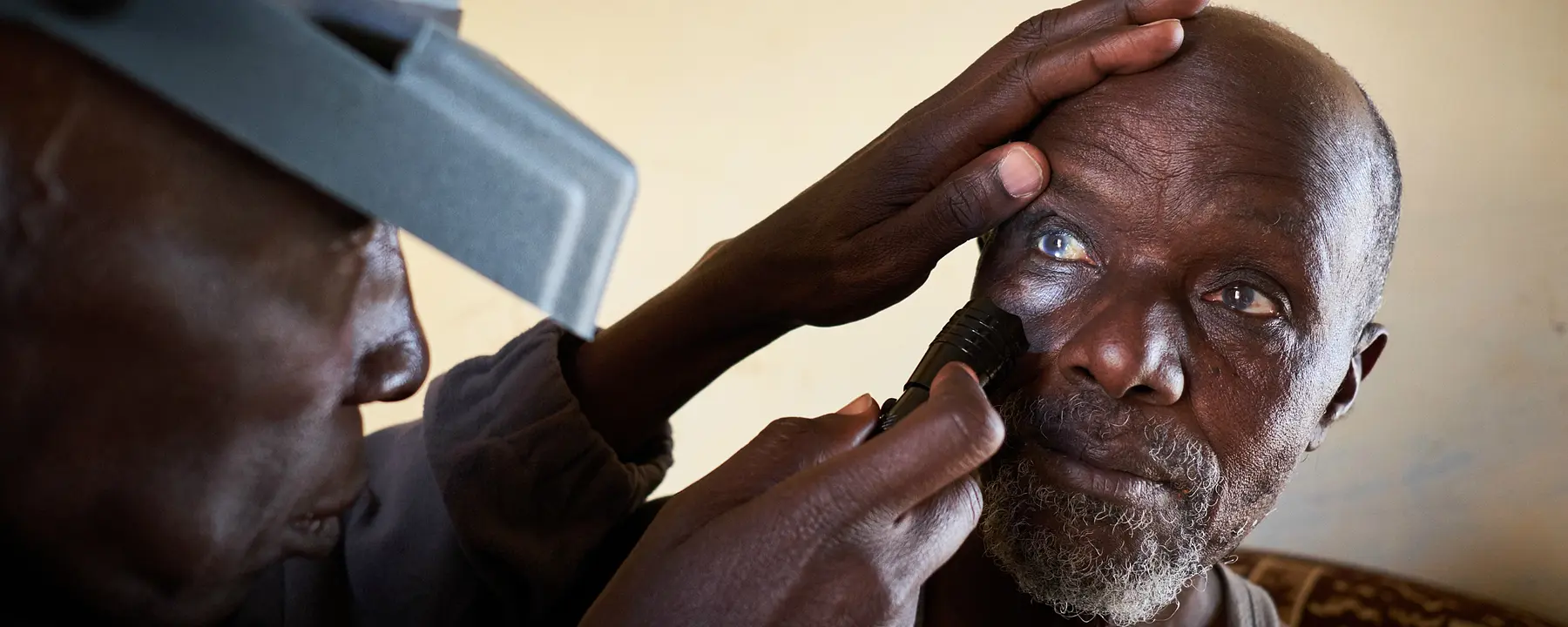 A health worker checks a man's eyes for signs of trachoma.