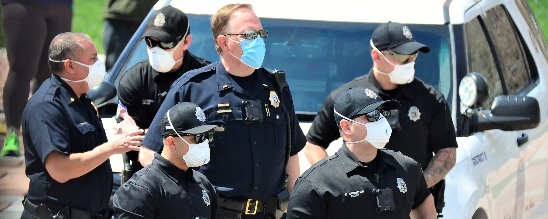 a group of police officers on scene are all wearing protective masks due to the COVID-19 pandemic