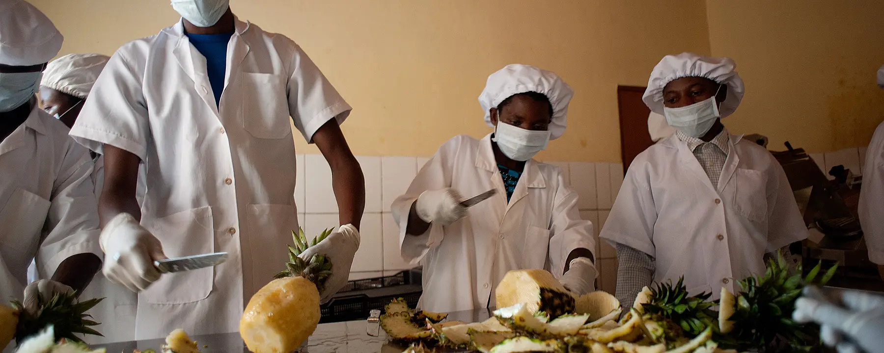 Rwandan food workers slicing pineapples