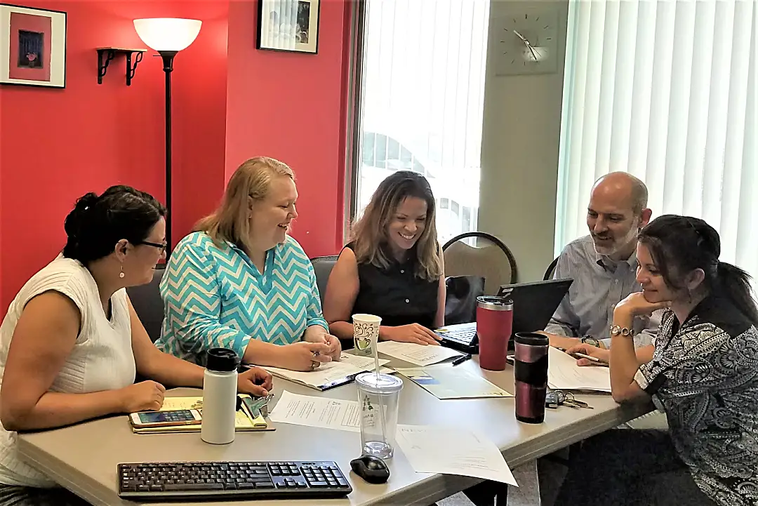 five people sitting around an office table