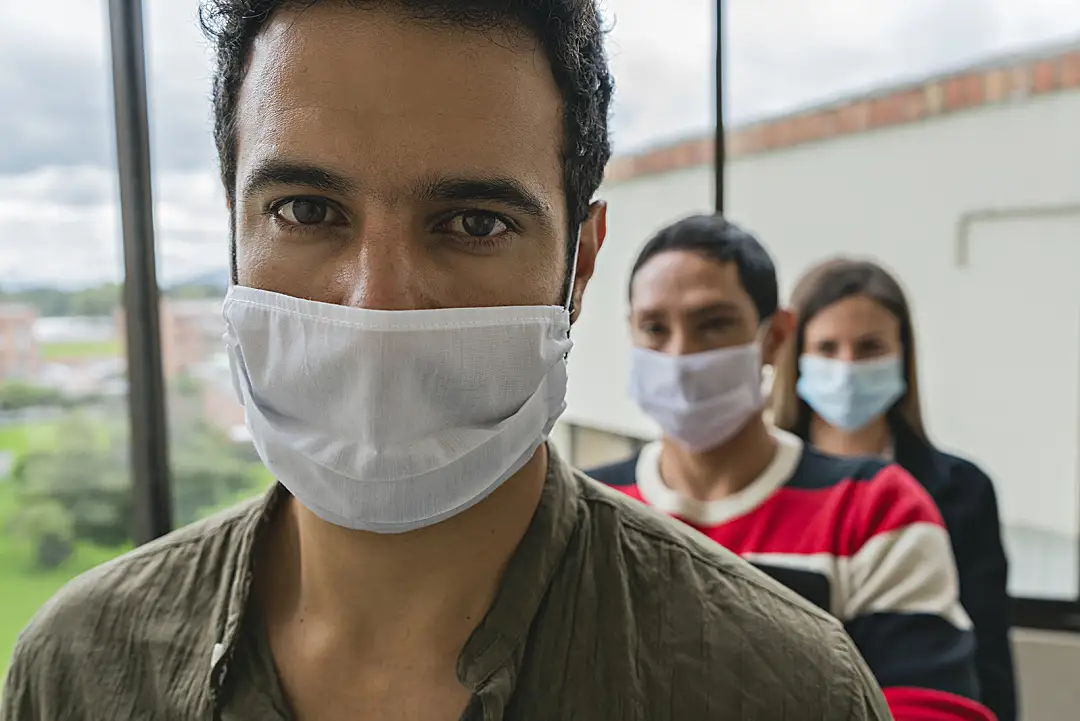 Several essential employees wearing masks climb the stairs at their workplace.