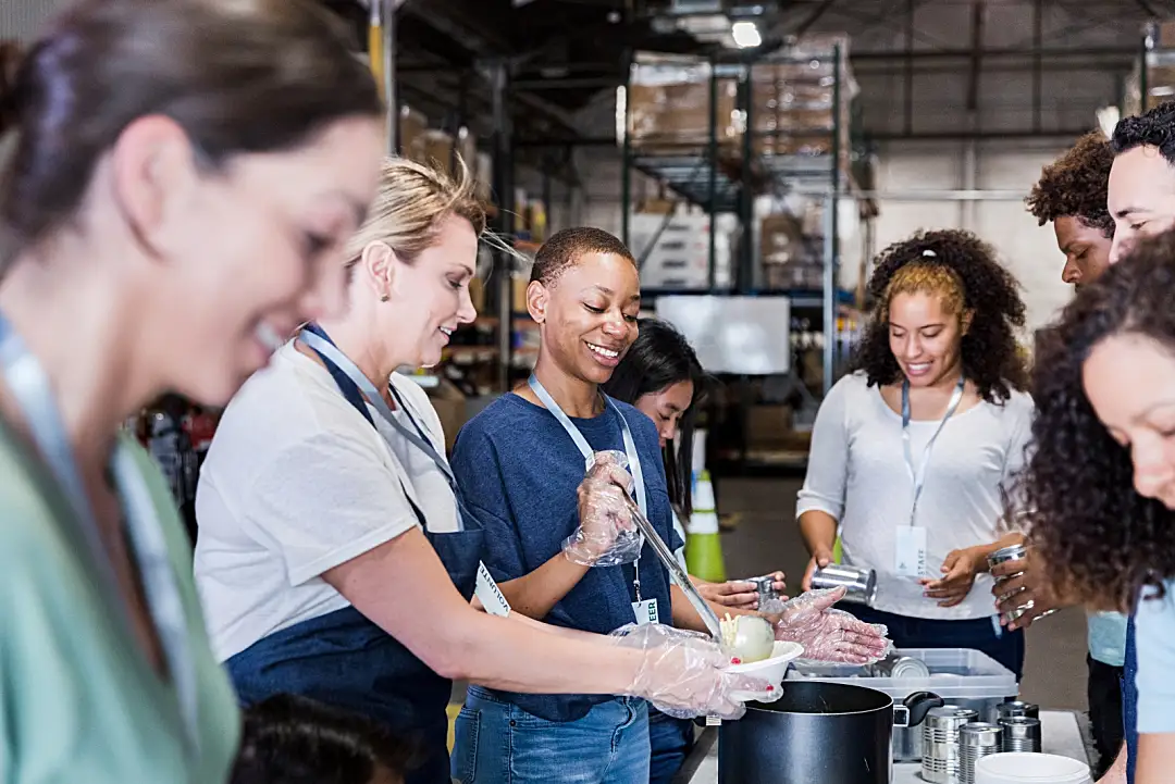 A group of volunteers smiling while preparing food