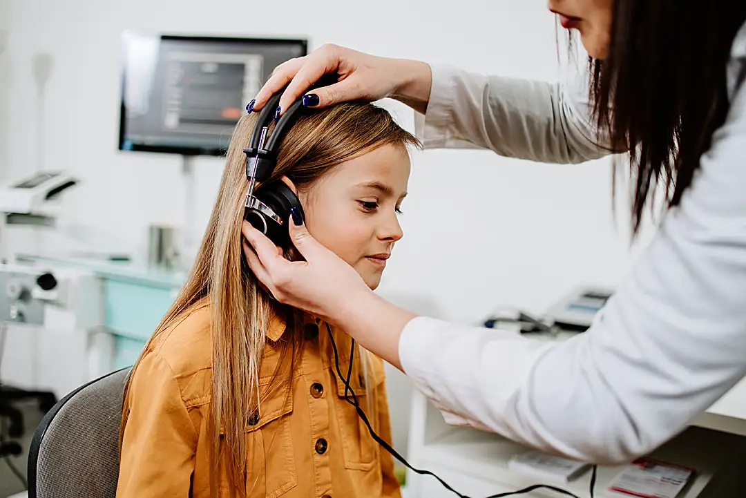 A middle-school girl gets a hearing test from an audiologist.