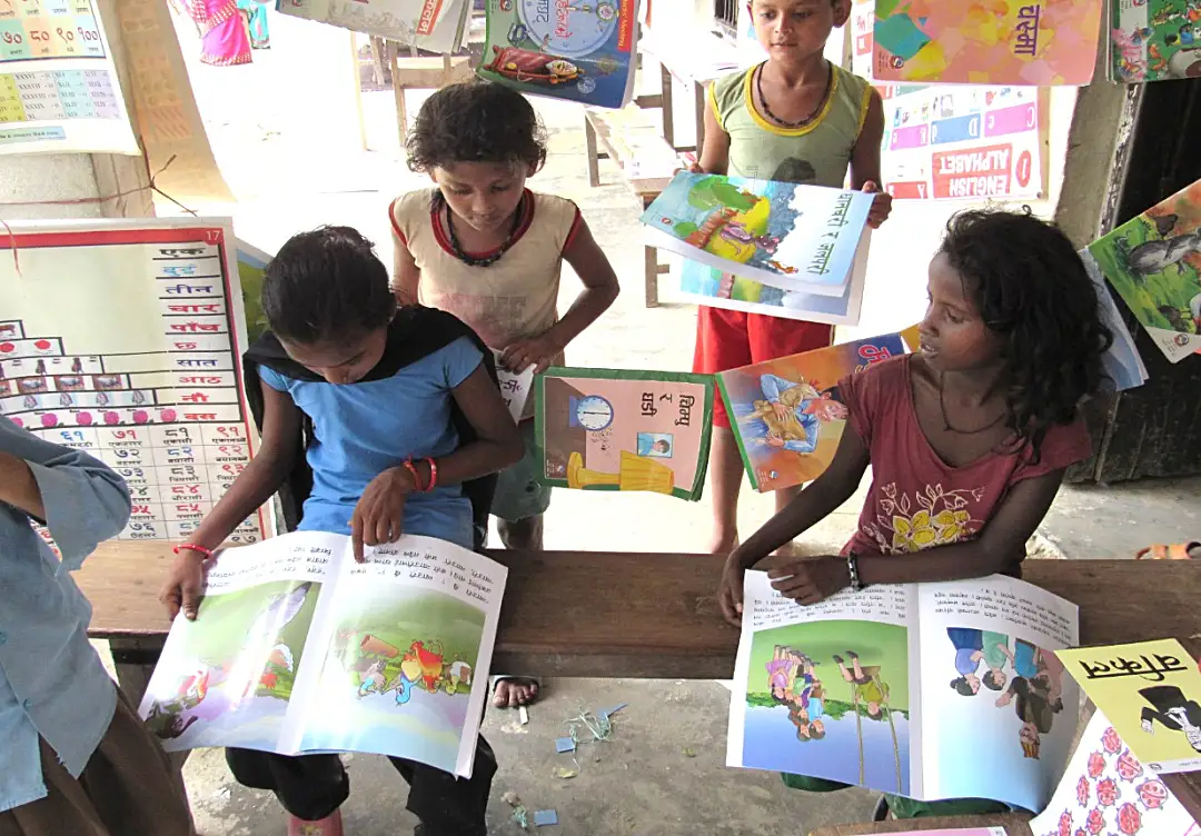 Schoolchildren read books printed in their native languages from the Nepal EGRP.