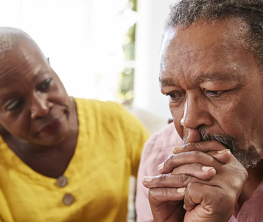 A senior Black couple with serious facial expressions.