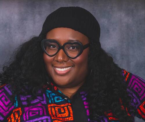 Headshot of Yewande Addie smiling against a grey background