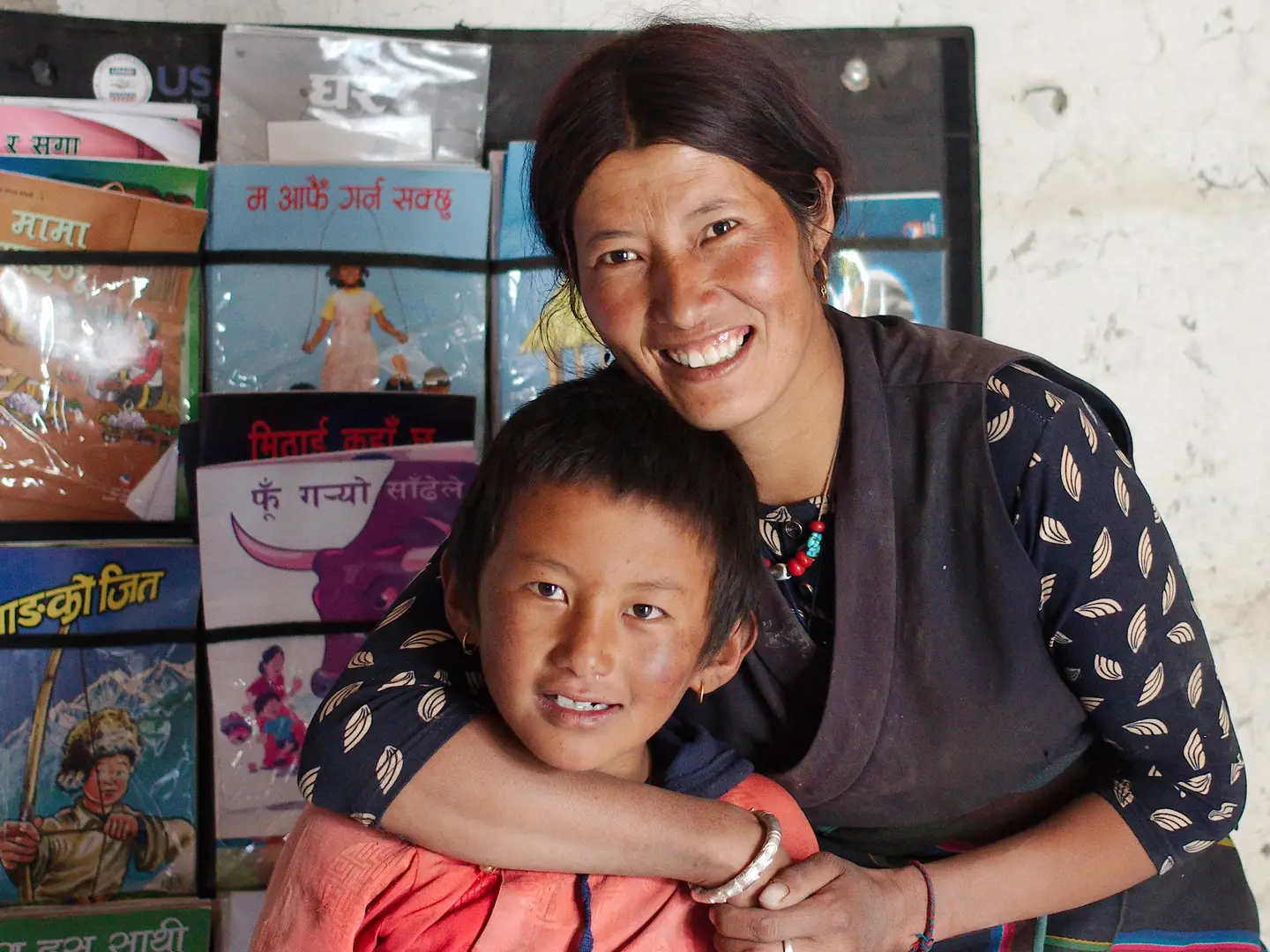 A mother and child pose with books from the Nepal Early Grade Reading program.