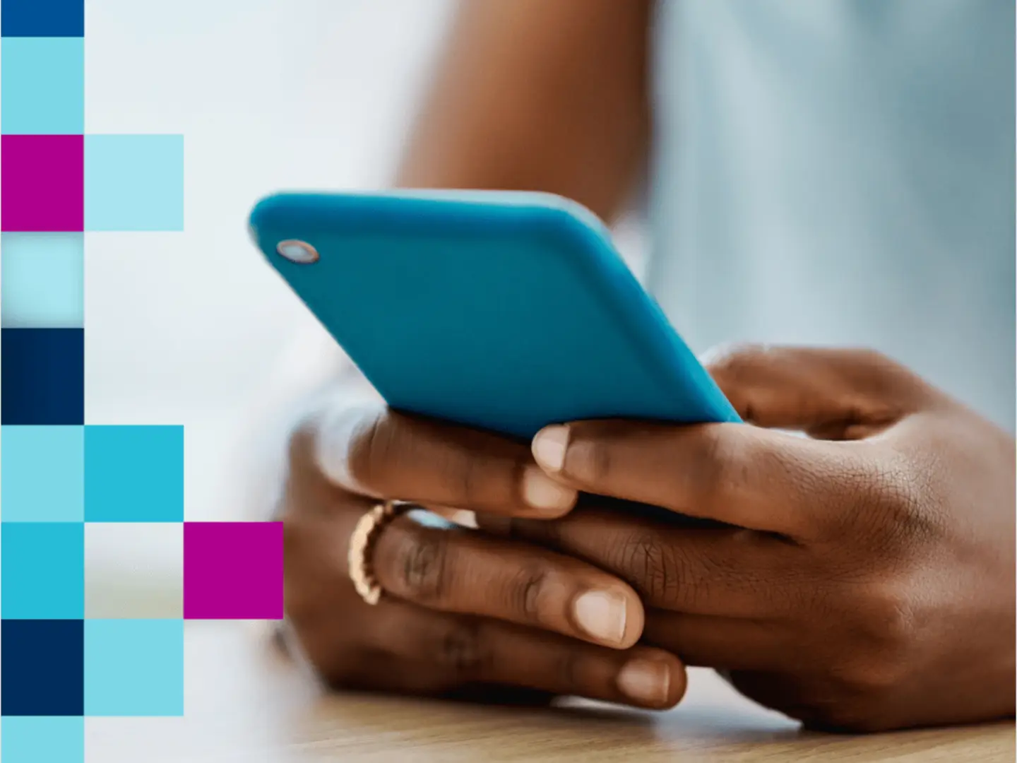 Hands holding a blue smartphone, with a colorful grid pattern on the left side.