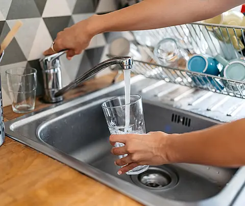Person fills glass cup with tap water