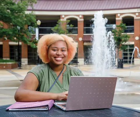 Young woman with laptop and binder