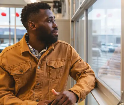 Seated man looks outside window