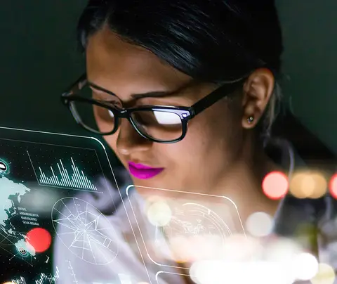 A person wearing glasses interacts with digital holograms in a tech-themed environment.