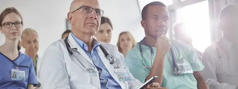 Doctors attentively listening during a lecture in a hospital conference room.