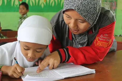 Young child and teacher reviewing educational materials