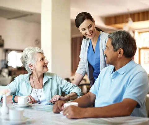 Two nursing-home residents, a woman and a man, talk with a female staff member.