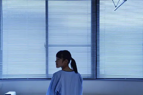 teen sitting on hospital bed in ward