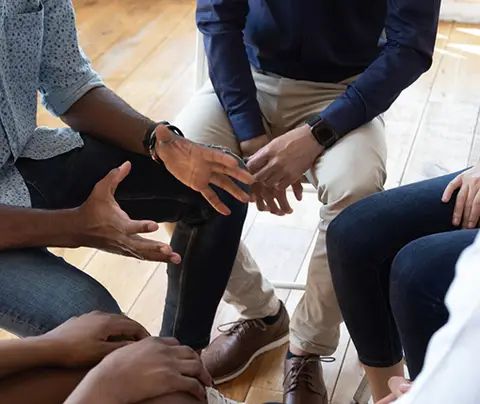 People sitting in a circle, engaging in a discussion.