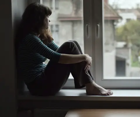 woman looks out window