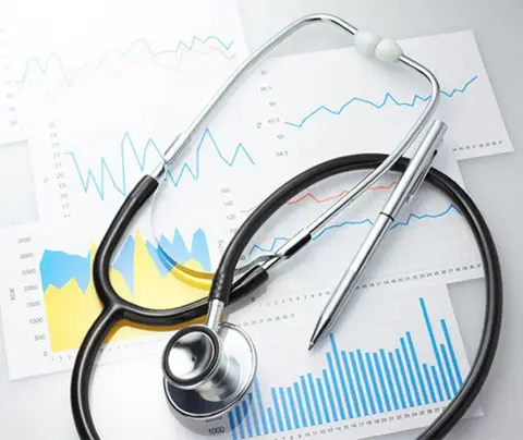 Stethoscope and pen resting on medical charts with various line and bar graphs.