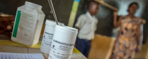 health worker measures a child to determine the right dose of an NTD medication